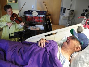 Music therapist Lucy Thomas plays for palliative care patient George Frederick, 91, at St. Paul's Hospital in Vancouver. ‘One thing I do know is that there is very little pain or no pain when I know (Thomas) is going to be here in the next little while to play a song,’ says Frederick. (Photo: Nick Procaylo, PNG)