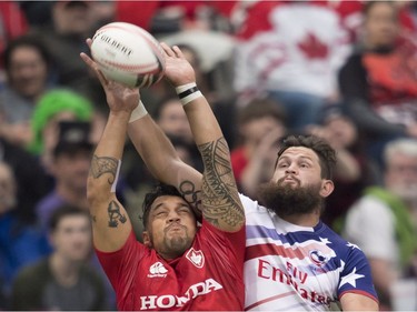 Canada's Mike Fuailefau, left, and Danny Barrett of the United States fight for control of the ball during the World Rugby Seven Series at B.C. Place in Vancouver, Saturday, March, 10, 2018.