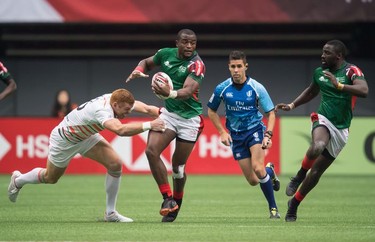 England's James Rodwell, left, tackles Kenya's Willy Ambaka, second left, as he passes to Samuel Oliech, right, during World Rugby Sevens Series action, in Vancouver, B.C., on Sunday March 11, 2018.