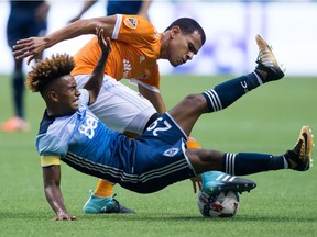 Vancouver Whitecaps' Yordy Reyna, front, is upended by Houston Dynamo's Juan David Cabezas during the first half of an MLS soccer game in Vancouver, B.C., on Saturday August 19, 2017.