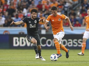 Vancouver Whitecaps midfielder Felipe Martins and Houston Dynamo midfielder Tomas Martinez  battle for control of the ball during the first half of Saturday's game at BBVA Compass Stadium.