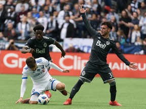 Montreal Impact defender Michael Petrasso battles with Vancouver Whitecaps midfielders Russell Teibert, right, and Alphonso Davies during the first half of the Caps' season-opener at B.C. Place earlier this month.