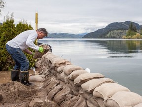 Malcolm Uttley places sandbags along his property as flood threatened parts of the Okanagan last year. Snowpacks are well above normal as spring approach this year, authorities say.