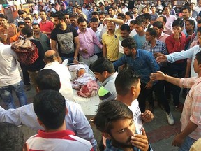 Indian people take injured to the hospital after a private school bus plunged off a cliff in Nurpur, Kangra district on April 9, 2018.