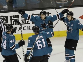 San Jose Sharks center Tomas Hertl, center, celebrates with Marc-Edouard Vlasic), Justin Braun and Logan Couture after scoring.