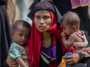 In this Sunday, Oct. 22, 2017, file photo, Rohingya Muslim woman, Rukaya Begum, who crossed over from Myanmar into Bangladesh, holds her son Mahbubur Rehman, left and her daughter Rehana Bibi, after the government moved them to newly allocated refugee camp areas, near Kutupalong, Bangladesh.