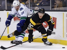 Henrik Sedin battles for the puck with the Boston Bruins' Riley Nash.