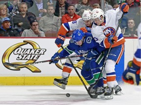 Brock Boeser and Mathew Barzal fight for possession of the puck during a game in Vancouver in March.