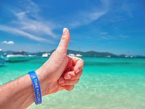 Concept excellent holiday at sea. Male hand with thumb up against turquoise sea and blue tropical sky.