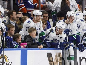 Vancouver Canucks' Daniel Sedin and Henrik Sedin watch the shootout on the bench with family members while playing against the Edmonton Oilers during NHL action in Edmonton on Saturday April 7, 2018.