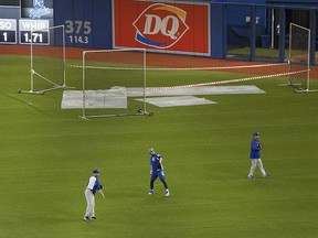 Kansas City Royals players throw baseballs in front of tarps protecting the Rogers's Centre field from water coming through the roof on Monday April 16, 2018. (THE CANADIAN PRESS/Fred Thornhill)
