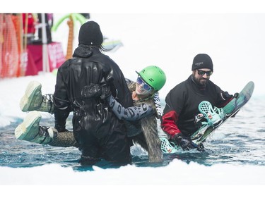 Snow patrollers help Katie Bodmer to shore after she crashed in the pond while competing in the  participate in the Grouse Mountain Slush Cup where competitors attempt to cross a pool of slush on their skis or board, North Vancouver  April 21 2018.