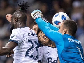 Vancouver Whitecaps' goalkeeper Stefan Marinovic, right, collides with teammate Jose Aja, centre, as he attempts to punch the ball away from Los Angeles Galaxy's Chris Pontius during MLS action in Vancouver on March 24.