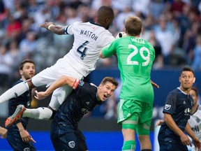 Sporting Kansas City's Matt Besler, centre, watches as goalkeeper Tim Melia grabs the ball away from the Whitecaps' Kendall Waston during MLS action in Vancouver on May 20, 2017.