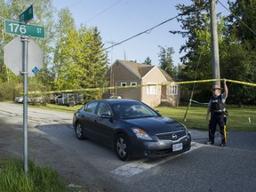 An RCMP officer lifts tape for officers leaving the site of a suspicious death on 12th Avenue between 176 Street and 184 Street in Surrey.