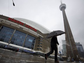 A man walks by the Rogers Centre as reports of falling ice from the CN Tower sparked a closure of parts of the area on Toronto on Monday, April 16, 2018.
