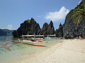 Bangkas pulled up near Secret Beach, which is accessed by swimming through a hole in the rock wall to the right.