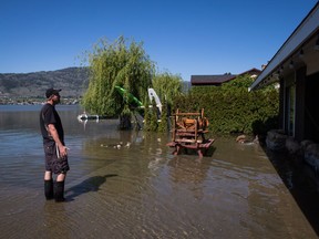 Steve Tye, of Surrey stands in the flooded yard of his lakefront summer home before checking on the level of water being pumped out of the crawl space, in Osoyoos, B.C., on Sunday, May 13, 2018. The Regional District of Kootenay Boundary says about 3,000 residents remain on evacuation order due to the ongoing threat of a second flood, with high forecasted temperatures expected melt snow at higher elevations.