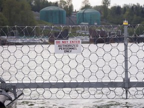 Oil tanks can be seen behind a floating chain link fence topped with razor wire in at the Kinder Morgan marine terminal in Burnaby.