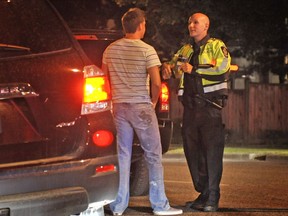A VPD officer discusses the alcohol roadside test procedure with a motorist at  a road block in 2011. How marijuana impairment in B.C. will be judged is still confusing.