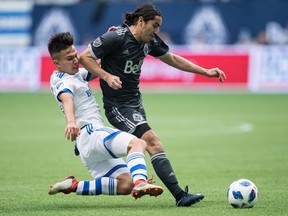 Montreal Impact's Ken Krolicki, left, slides to tackle Vancouver Whitecaps' Efrain Juarez during the first half of an MLS soccer game in Vancouver, B.C., on Sunday March 4, 2018.