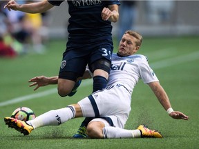 Vancouver Whitecaps' Brett Levis, right, slides to take the ball away from Sporting Kansas City's Cameron Porter during first half CONCACAF Champions League soccer action in Vancouver, B.C., on Tuesday August 23, 2016. The Vancouver Whitecaps have announced that Brett Levis underwent successful surgery on his right knee.