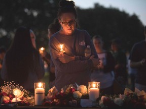 Catherine Casper sstands amid various momentos people have left during a candelight vigil in Santa Fe, Texas for the victims of the mass shooting on May 18, 2018. Ten people, mostly students, were killed when a teenage classmate armed with a shotgun and a revolver opened fire in a Texas high school May 18, 2018, the latest deadly school shooting to hit the United States.