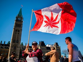 In this file photo taken on April 20, 2016 showing a woman waving a flag with a marijuana leef on it next to a group gathered to celebrate National Marijuana Day on Parliament Hill in Ottawa.