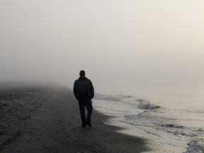 Lonely man walking on a foggy beach