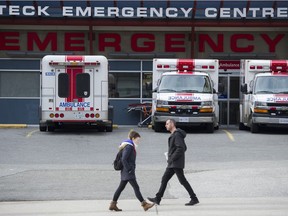 People walk past ambulances in the emergency bay at St. Paul's Hospital in Vancouver.