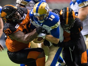 Winnipeg Blue Bombers quarterback Alex Ross, centre, is sacked by B.C. Lions' Odell Willis, right, as Davon Coleman during Friday's CFL pre-season action at B.C. Place Stadium in Vancouver.