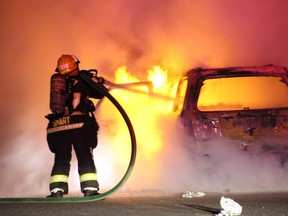 Firefighters work to put out a blaze in a vehicle linked to a double targeted shooting in Surrey in June 2017.