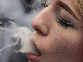 A woman exhales while smoking a joint during the 4-20 annual marijuana celebration, in Vancouver, on Friday April 20, 2018.