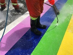 Surrey city workers clean a rainbow crosswalk after someone disfigured it.