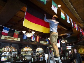 Jamie Young, events manager for Doolin's Pub, puts up flags to decorate the pub for the World Cup, in Vancouver on June 13.