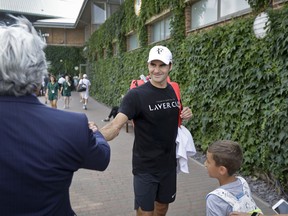 Roger Federer of Switzerland shakes hands with a well-wisher after a practice session ahead of the start of the Wimbledon Tennis Championships in London, Sunday, July 1, 2018. The Championships will start on Monday, July 2.