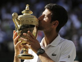 Novak Djokovic of Serbia holds the trophy after defeating Kevin Anderson of South Africa in the men's singles final match at the Wimbledon Tennis Championships in London, Sunday July 15, 2018.