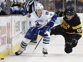 Troy Stecher of the Vancouver Canucks, left, and Tim Schaller of the Bruins battled last year during NHL action in Boston. This season they're both on the same team and the Canucks hope they'll help the squad make major improvements.
