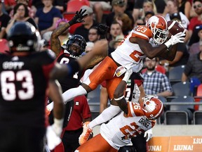 Anthony Thompson of the B.C. Lions falls over teammate Anthony Orange, right, as he attempts to pick off a pass intended for R.J. Harris of the Ottawa Redblacks during Friday's CFL action at TD Place Stadium in Ottawa.