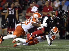 R.J. Harris of the Ottawa Redblacks tries to leap past the tackle of B.C. Lions' Jordan Herdman, left, and Winston Rose during Friday's CFL action at TD Place Stadium in Ottawa. The Redblacks won 29-25.