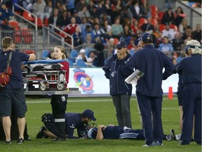 Medical assistants, coaching staff and players gather around fallen Toronto Argonauts quarterback Ricky Ray as he lays injured on the field during their CFL game against the visiting Calgary Stampeders on June 23, 2018.