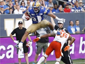 Winnipeg Blue Bombers' Andrew Harris (33) leaps over BC Lions' Anthony Orange (26) during the first half of CFL action in Winnipeg Saturday, July 7, 2018.