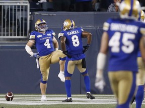 Winnipeg Blue Bombers' Adam Bighill (4) and Chris Randle (8) celebrate Bighill's interception and touchdown against the BC Lions' during the second half of CFL action in Winnipeg Saturday, July 7, 2018.