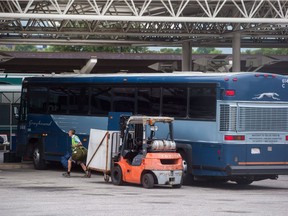 Package delivery firms say they're prepared to fill the gap when Greyhound Canada closes most of its Western Canada operations this October. A worker removes luggage from a Greyhound bus upon arrival in Vancouver on July 9.