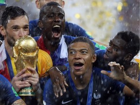 Kylian Mbappe (front centre) with his teammates celebrate with the World Cup trophy after France defeated Croatia in the championship final in Moscow on Sunday, July 15, 2018.
