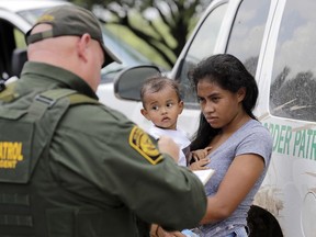 A mother migrating from Honduras holds her one-year-old child while surrendering to U.S. Border Patrol agents after illegally crossing the border, near McAllen, Texas, on June 25, 2018.