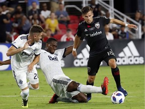 Vancouver Whitecaps defenders Jake Nerwinski (28) and Doneil Henry, center, work against D.C. United midfielder Zoltan Stieber (18) during the second half of an MLS soccer match at Audi Field, Saturday, July 14, 2018, in Washington. DC United won 3-1.