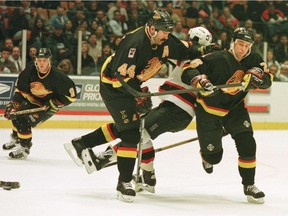 Vancouver Canucks Russ Courtnall Dave Babych and Mike Sillinger (left to right) are back in black for the Canucks circa 1995, taking out a New Jersey Devils player during an NHL game in the Meadowlands.