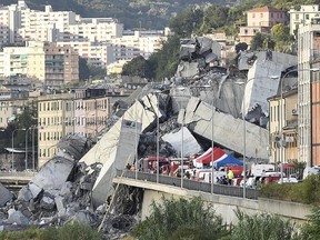 Rescuers work to recover an injured person after the Morandi highway bridge collapsed in Genoa, northern Italy, Tuesday, Aug. 14, 2018.