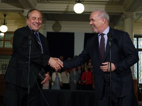 Green party Leader Andrew Weaver, left, shakes hands with NDP Leader John Horgan last year after signing an agreement on creating a stable minority government.